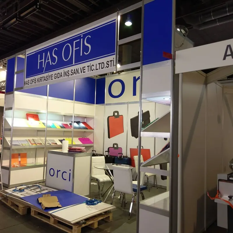 Weiß-blauer Messestand mit offenen Regalen, bunten Produkten und Glasvitrine.