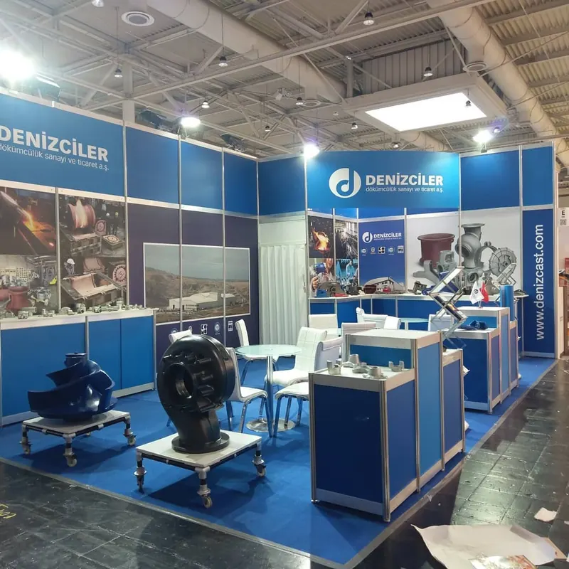 Blau-weißer Messestand mit großen Metallkomponenten und mehreren Produktpodesten.