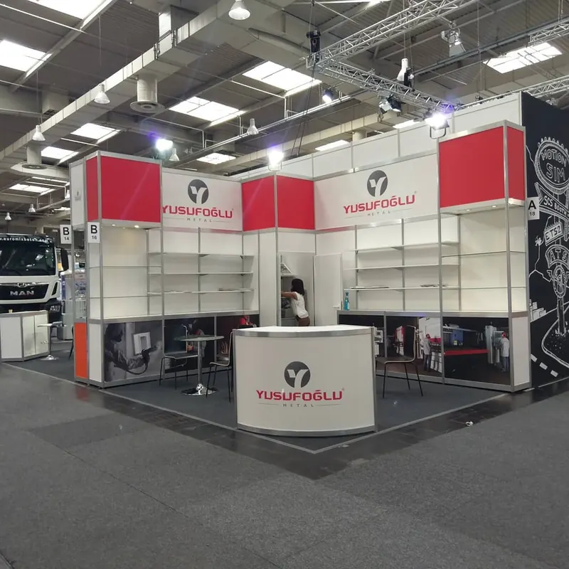 Weiß-roter Messestand mit offenen Wandregalen und einer weißen Empfangstheke.