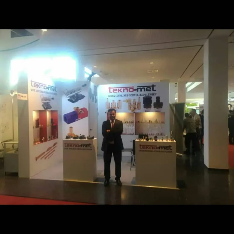 Heller Messestand mit roten Produktgrafiken, zwei Theken und einer Person davor.