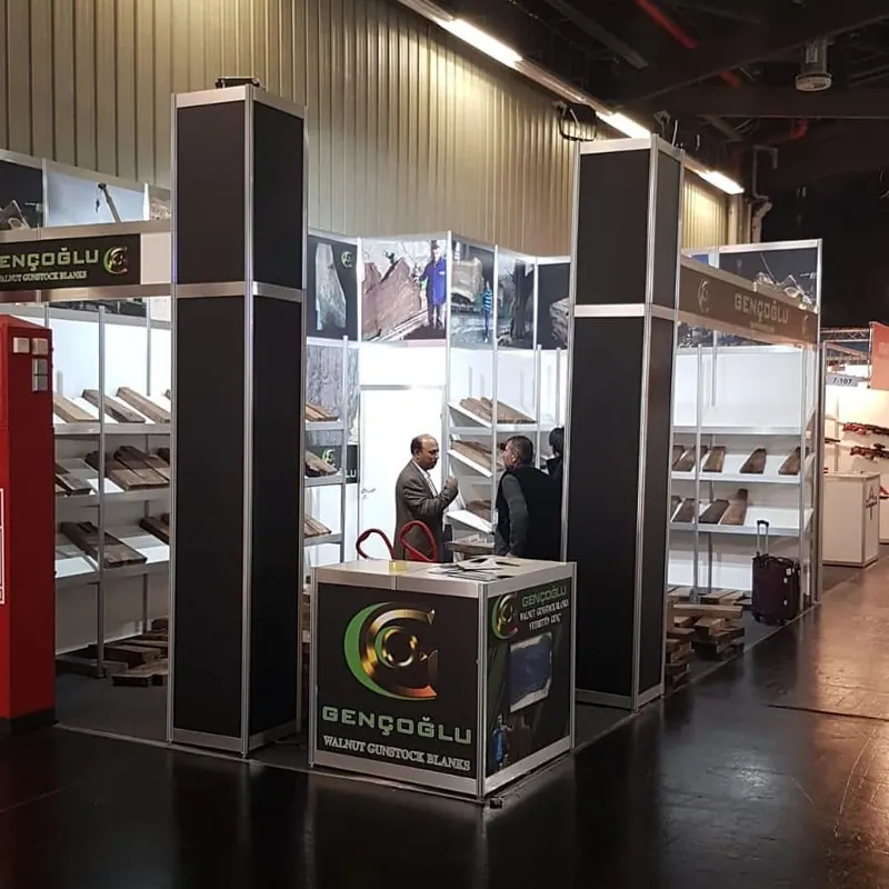 Schwarz-weißer Messestand mit hohen Eckstützen und vielen braunen Mustern auf Regalen.