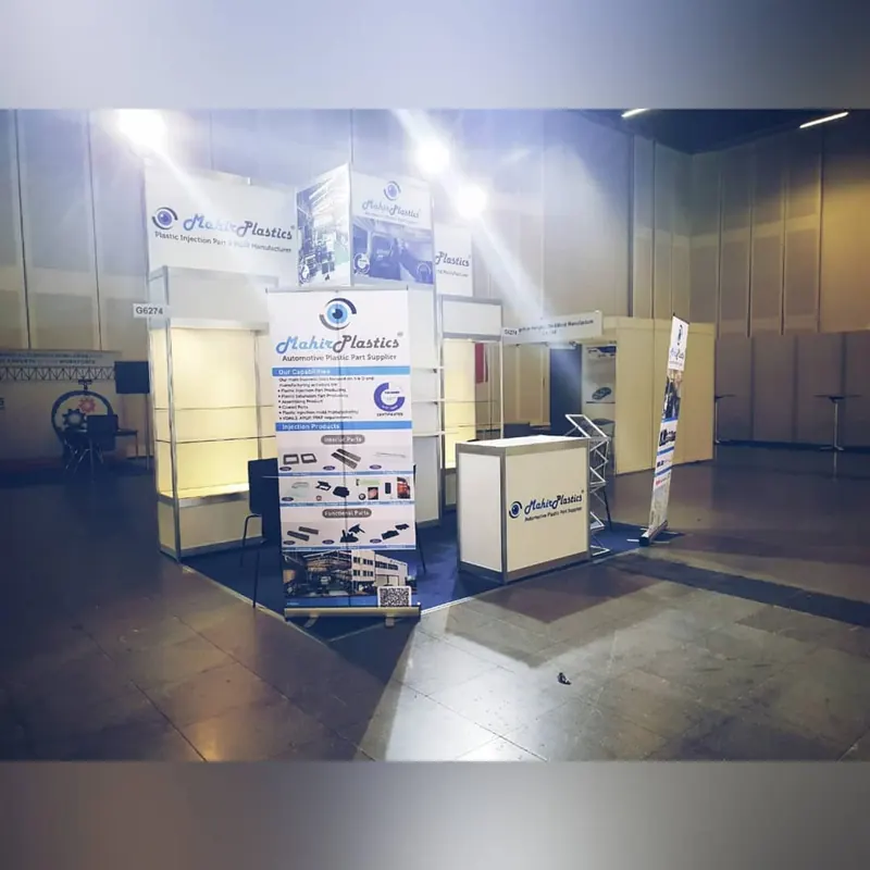 Heller Messestand mit hohen Produktbannern, offenen Rahmen und kleiner Theke.