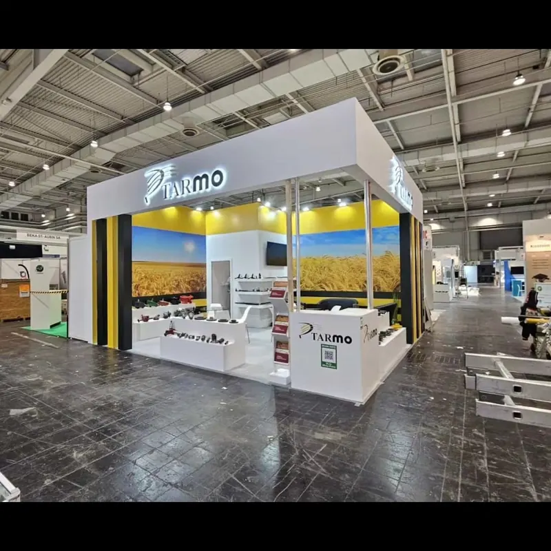 Weiß-gelber Messestand mit Landschaftsgrafik, hohen Rahmen und Produktpodesten.