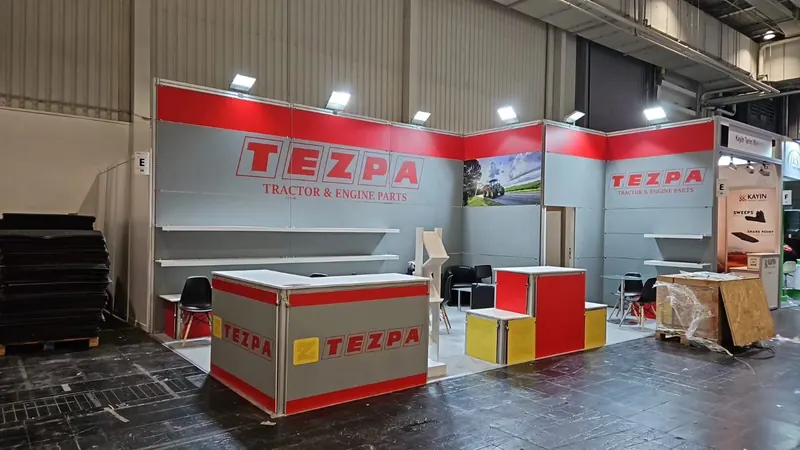 Rot-weißer Messestand mit breiten Theken, Produktgrafiken und verpackten Bauteilen.