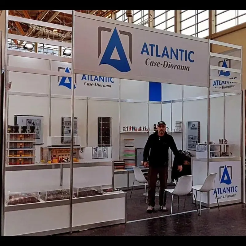 Weiß-blauer Messestand mit Glasvitrinen und schmalen Produktregalen.