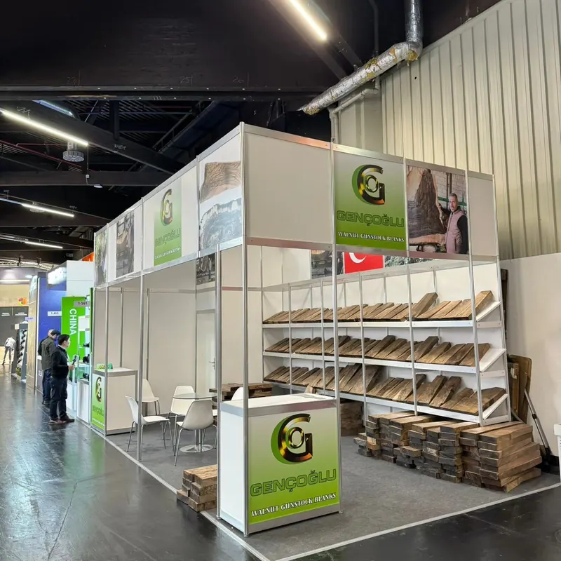Weiß-grüner Messestand mit hohen Regalrahmen und vielen gestapelten Produktmustern.