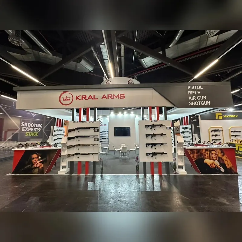 Weißer offener Messestand mit roten Streifen und horizontalen Produktregalen.