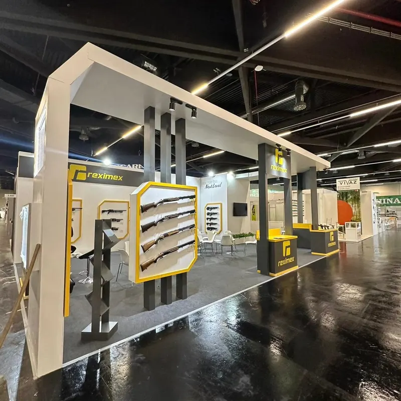 Weiß-gelber Messestand mit hohen Portalrahmen und langen Produktständern.