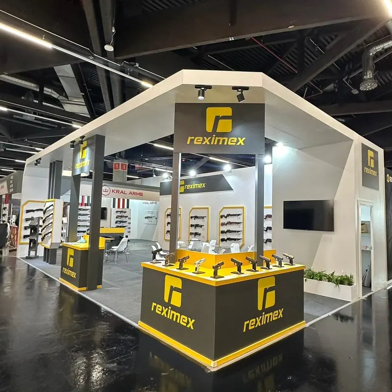 Weiß-gelber Messestand mit offenem Deckenrahmen und Wanddisplays für Langwaffen.