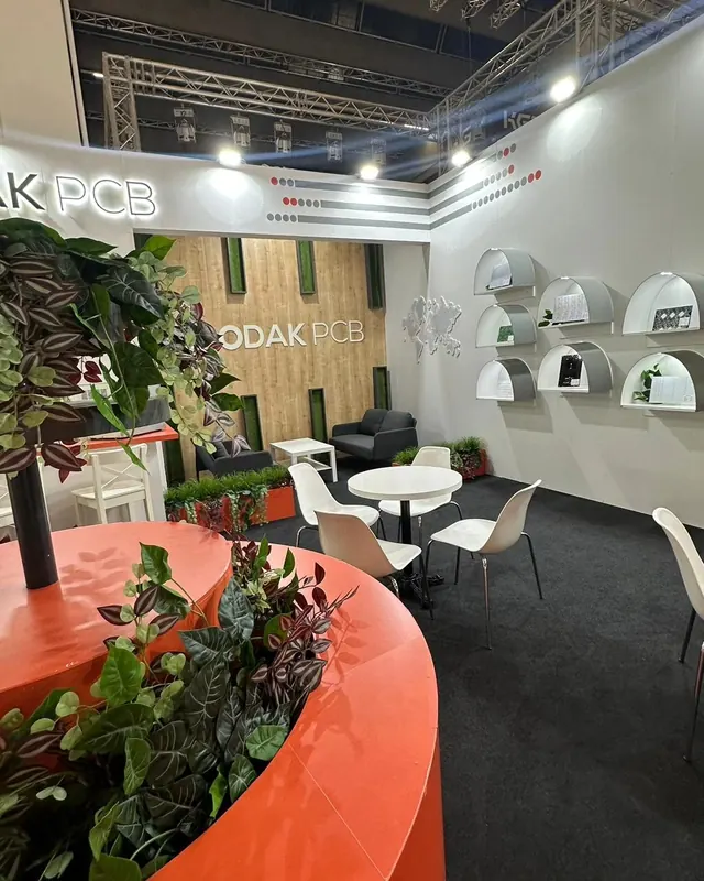 Rot-orange geschwungene Pflanzentheke vor weißen Sitzgruppen und einer Wand mit Produktschalen.