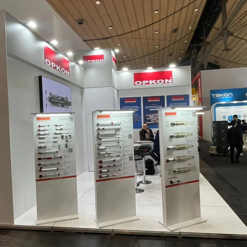 Weiße Produktdisplays mit senkrecht angeordneten Metallteilen vor einer weiß-roten Standwand.