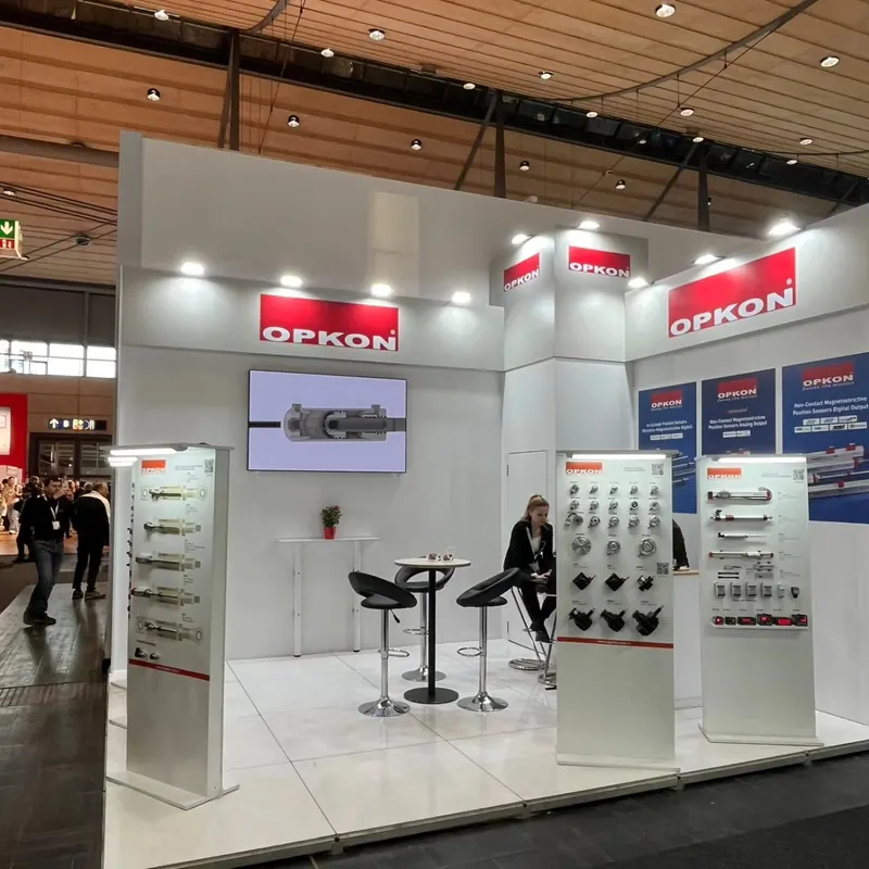 Weiße Produktdisplays mit senkrecht angeordneten Metallteilen vor einer weiß-roten Standwand.