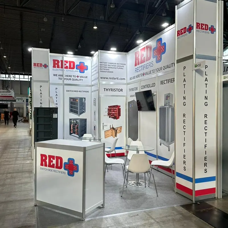 Weißer Messestand mit rot-blauen Akzenten, Produktgrafiken und weißen Sitzgruppen.