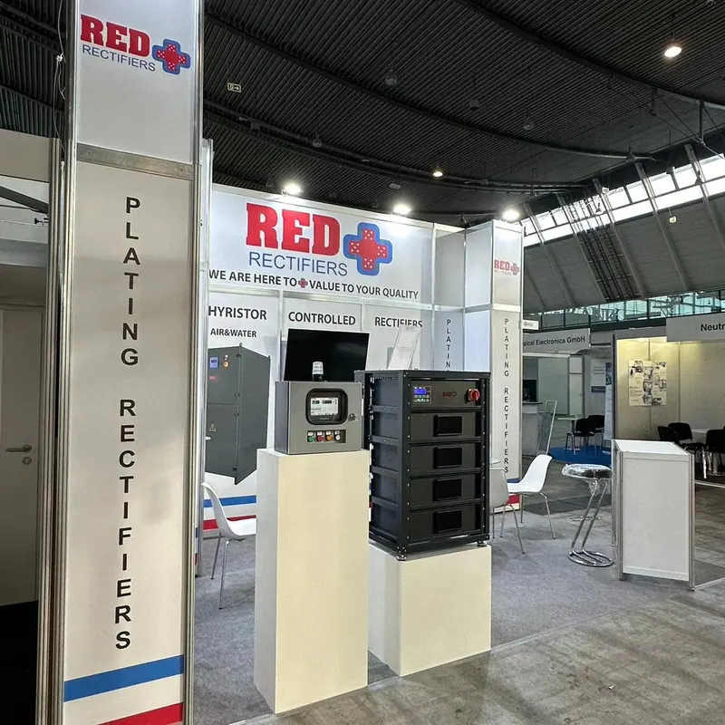 Weiße Produktpodeste mit technischen Geräten vor rot-blauen Standgrafiken.