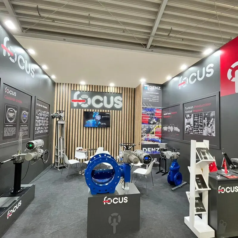 Grauer Messestand mit Holzlamellen, Bildschirm und blauen Ventilexponaten.