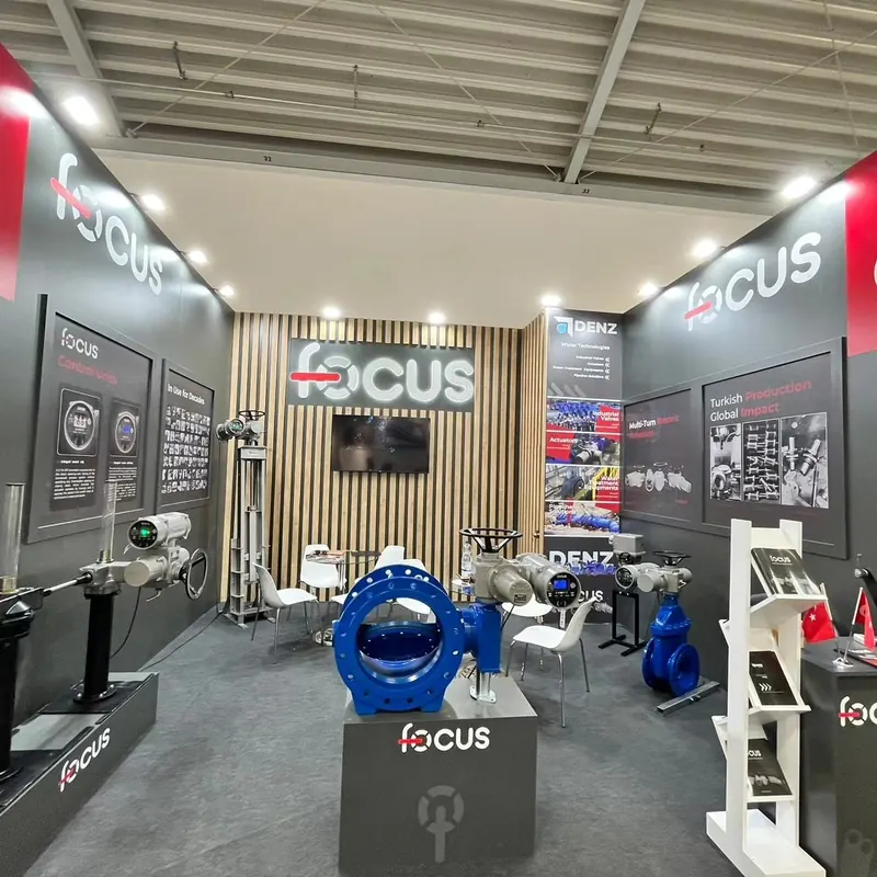 Grauer Messestand mit Holzlamellen, Bildschirm und blauen Ventilexponaten.