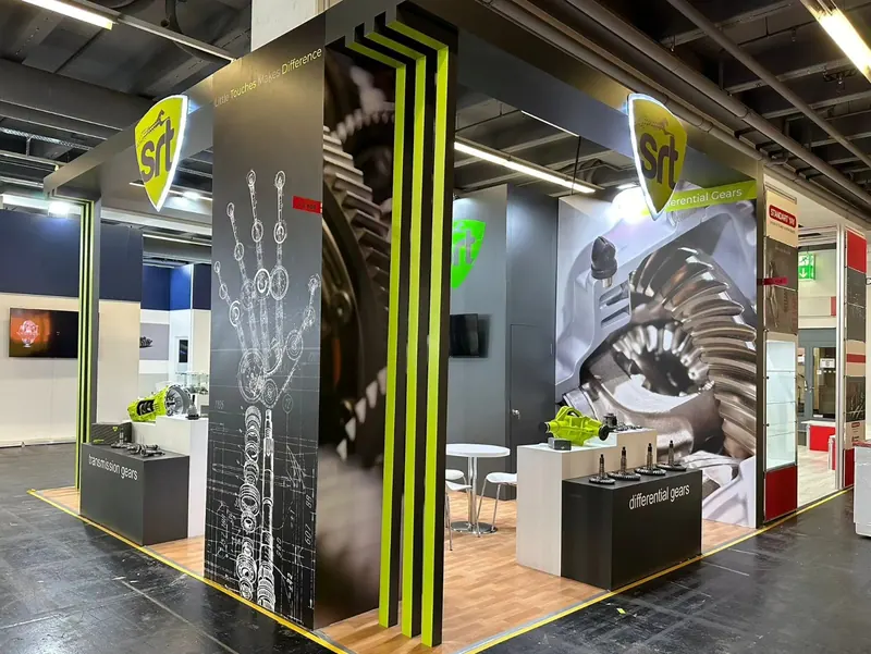 Messestand mit schwarz-grauen Säulen, grünen Linien und großen Zahnraddarstellungen.