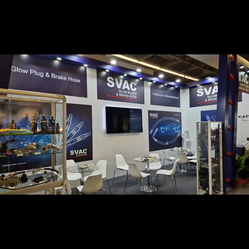 Weiß-blauer Messestand mit Glasvitrine, Bildschirm und weißen Sitzgruppen.