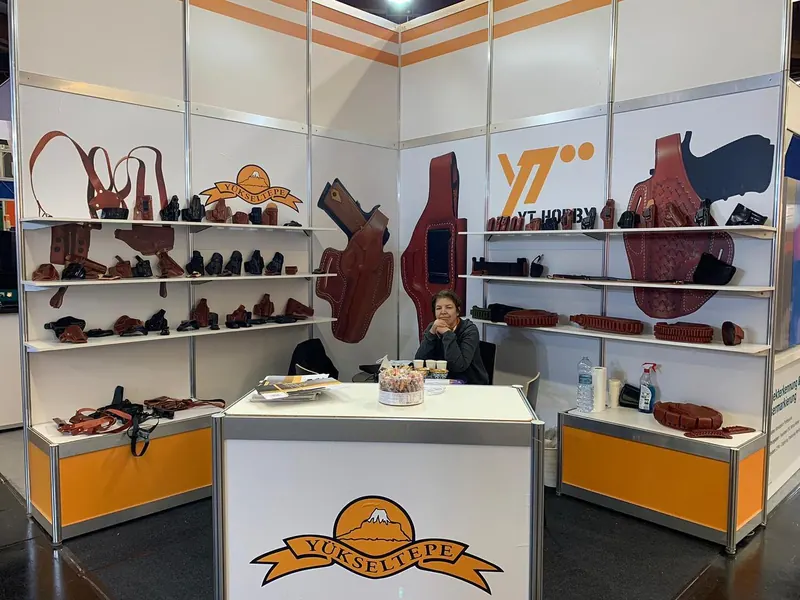 Weiß-oranger Messestand mit Taschen- und Schuhmustern auf offenen Regalen.