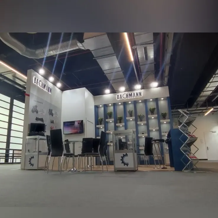 Weiß-blauer Messestand mit hohen Regalen, kleinen Produktmustern und schwarzen Barhockern.