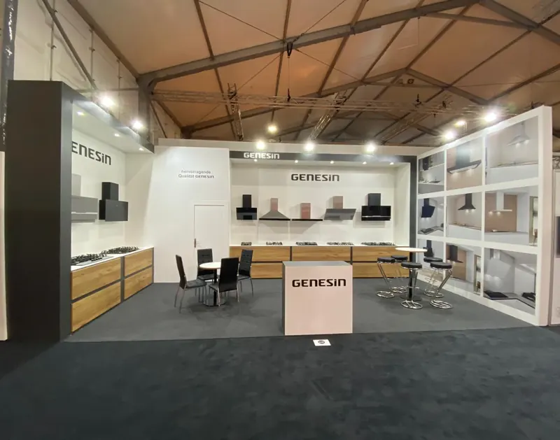 Messestand mit weißen Präsentationsregalen, einer hellen Theke und Sitzgruppen.