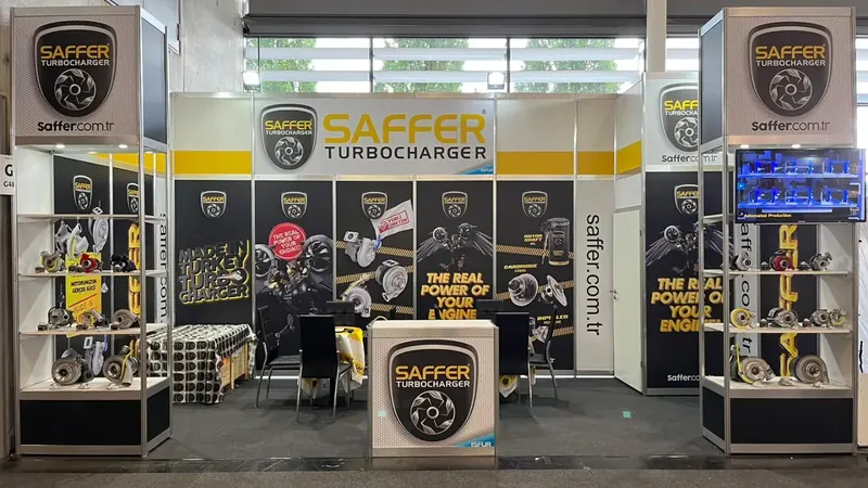 Schwarz-gelber Messestand mit Glasvitrinen, mechanischen Bauteilen und mittiger Theke.