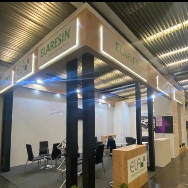 Heller Messestand mit hohem Portal, schwarzen Stützen und dunklen Besprechungsstühlen.