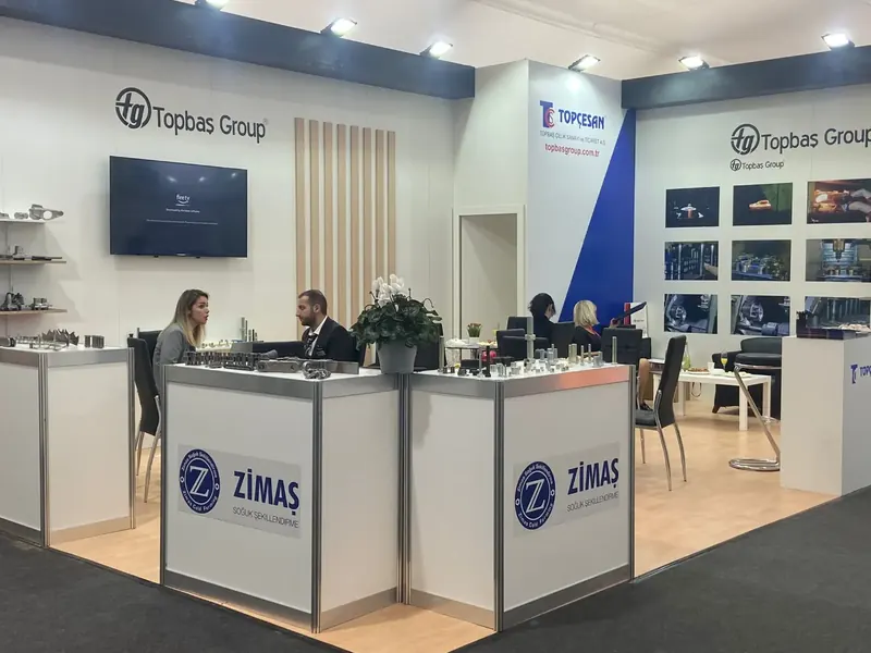 Blau-weißer Messestand mit großen Theken, Pflanzen und senkrechten Holzoptiklamellen.