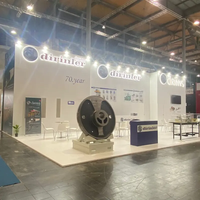 Weißer Messestand mit großer runder Metallkomponente und beleuchteten Markenwänden.