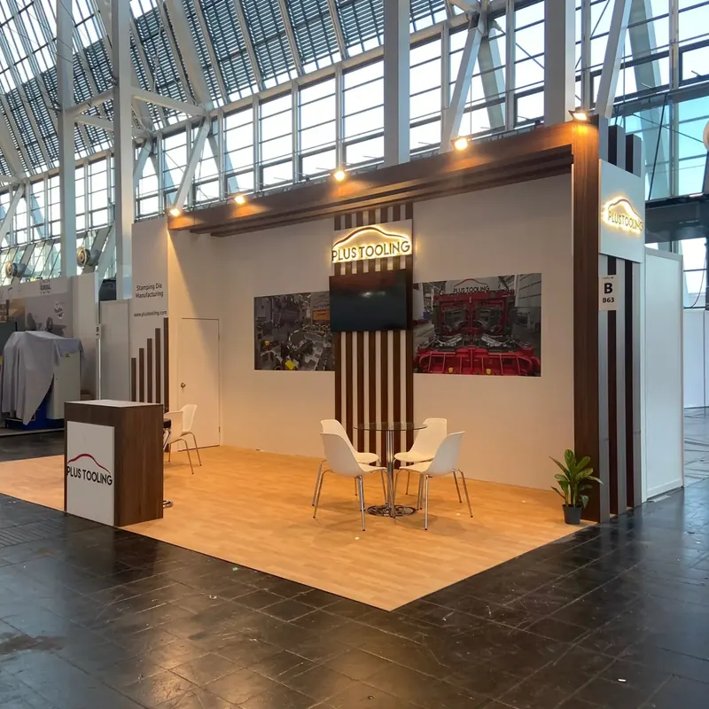 Messestand mit Holzoptikboden, dunklen Lamellen und warm beleuchteter Rückwand.