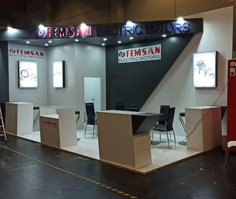 Dunkelgrau-weißer Messestand mit beleuchteten Schildern und kantigen hellen Podesten.