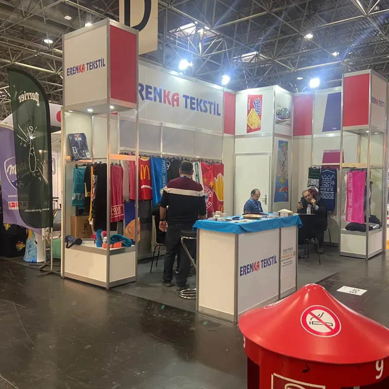 Weiß-roter Messestand mit bunten Stoffbahnen und kleiner blau-weißer Theke.