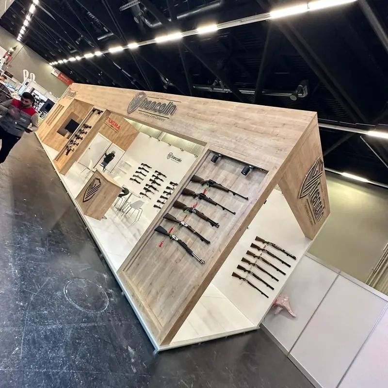 Messestand in heller Holzoptik mit schrägen Rahmen und langen Produktmustern.