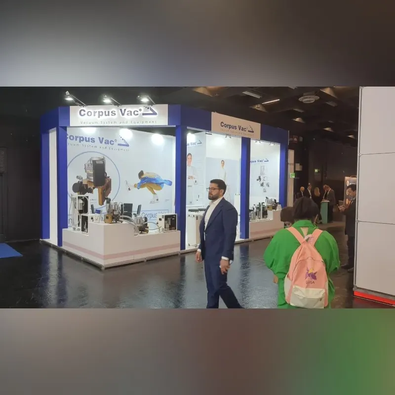 Weiß-blauer Messestand mit Produktgrafiken, technischen Exponaten und Besuchern davor.