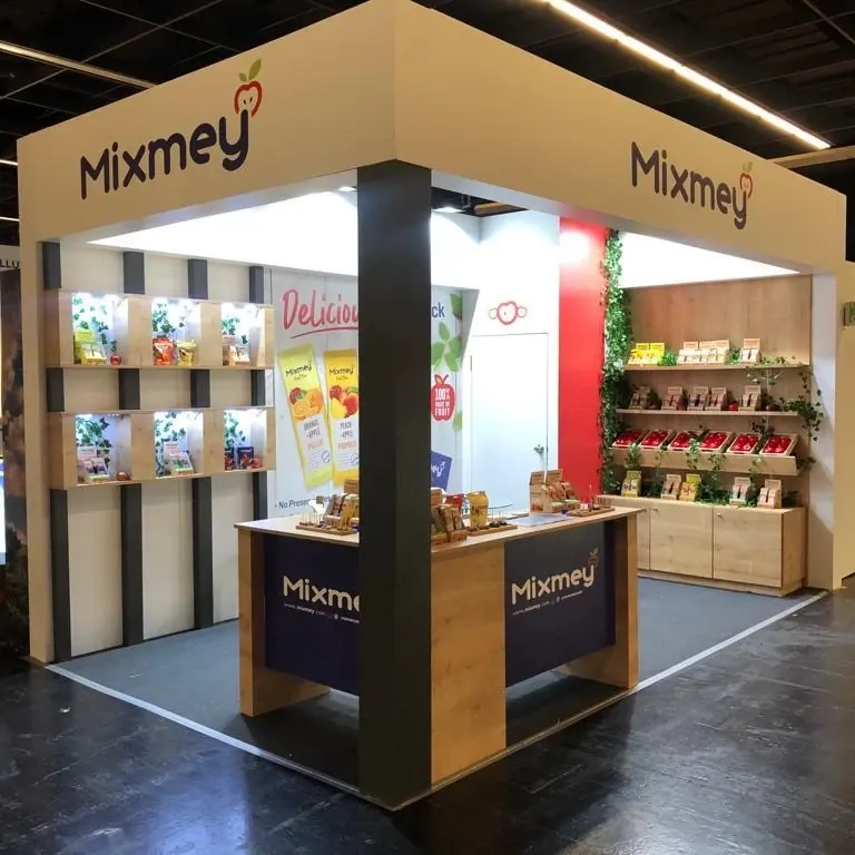 Messestand mit Holzrahmen, dunklen Säulen und Regalen voller bunter Verpackungen.