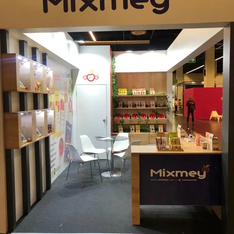 Messestand mit Holzrahmen, dunklen Säulen und Regalen voller bunter Verpackungen.