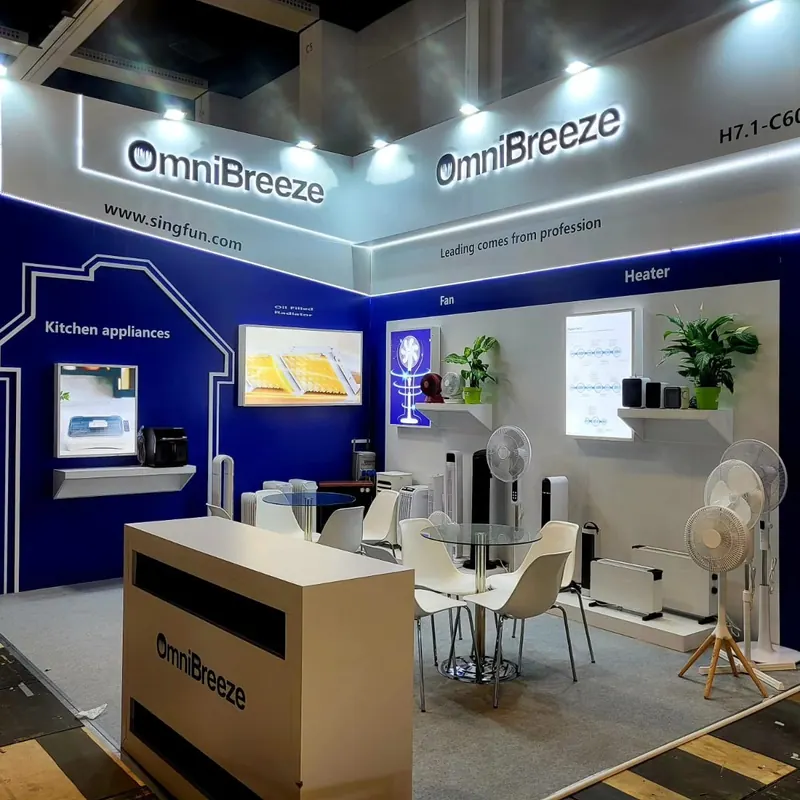Blau-weißer Messestand mit Küchengeräten, Ventilatoren und kleiner Sitzgruppe.