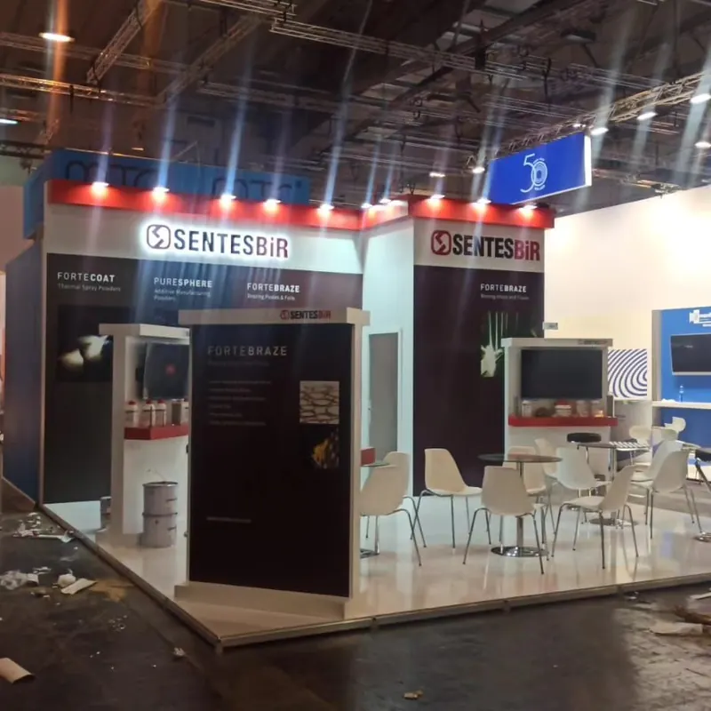 Weißer Messestand mit roten Rahmen, dunklen Grafikflächen und weißen Sitzgruppen.
