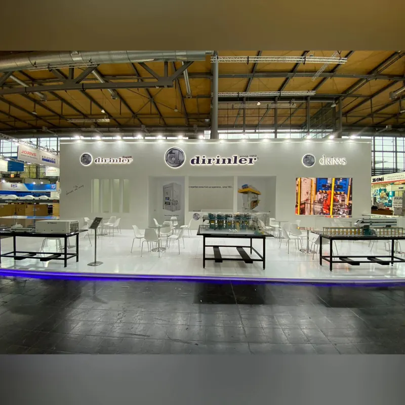 Weißer offener Messestand mit langen Metalltischen und blau beleuchtetem Bodenrand.