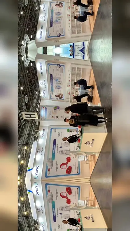 Reel-Vorschaubild: Weiß-blauer Messestand mit roten Produktgrafiken und mehreren Personen.