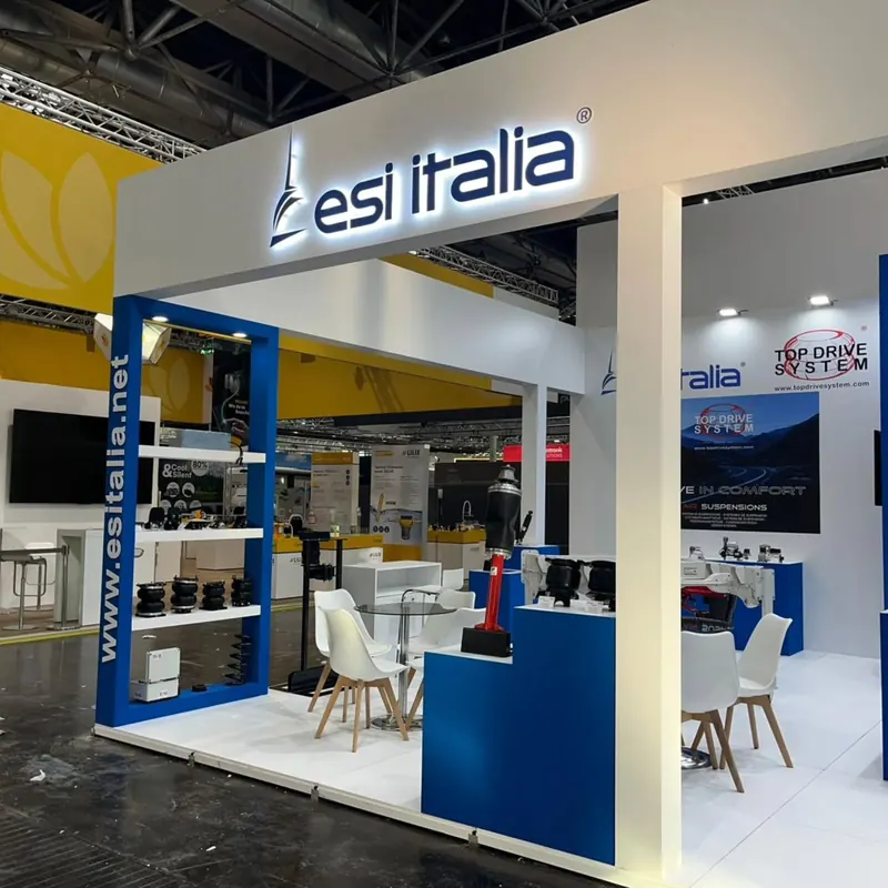 Weiß-blauer Messestand mit offenen Produktregalen und weißen Stühlen.