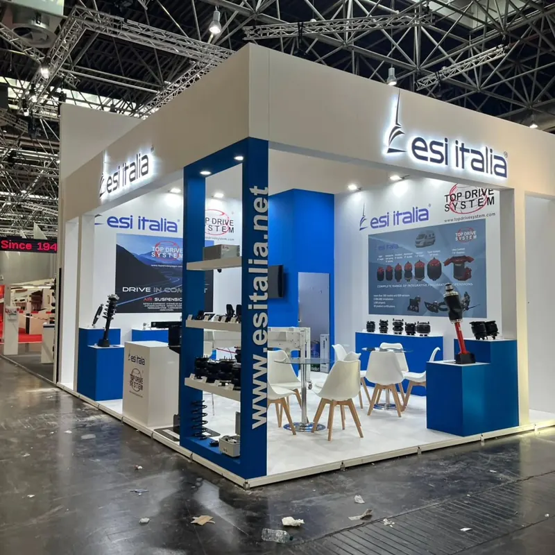 Blau-weißer Messestand mit hohen Wänden, Produktpräsentationen, Theken und einer Sitzgruppe.