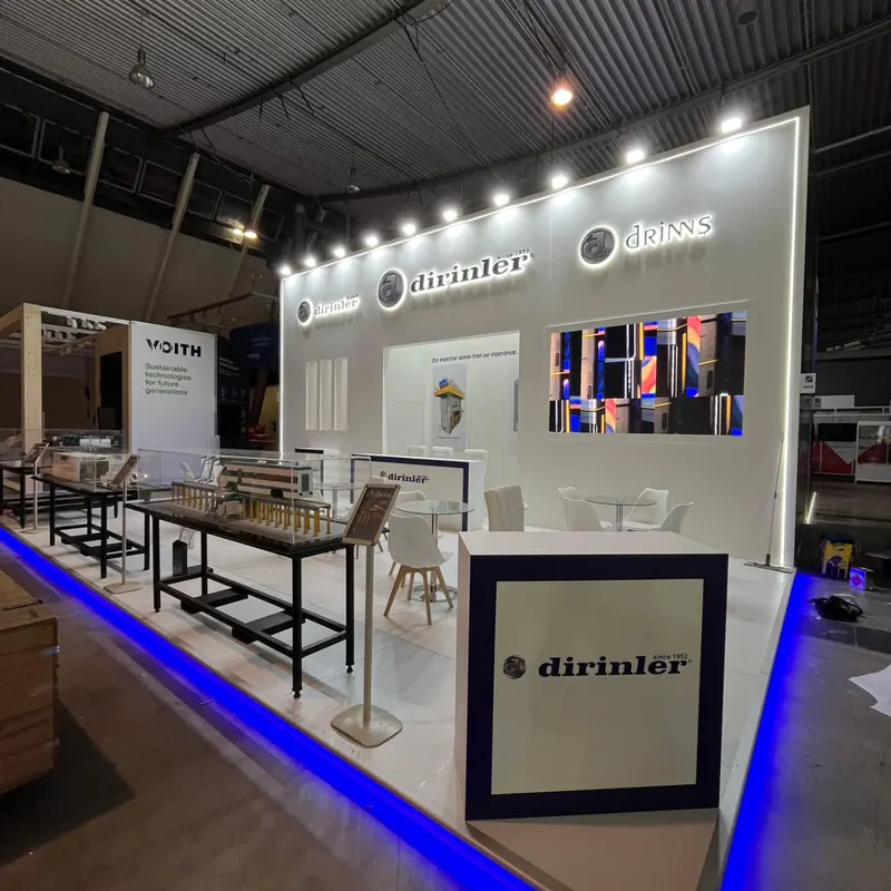 Weißer Messestand mit Maschinen auf schwarzen Tischen und blauer Bodenkantenbeleuchtung.