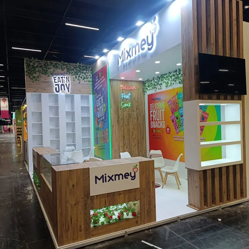 Weiße Standfront mit Holztheke, Pflanzenfach und farbigen Fruchtgrafiken.