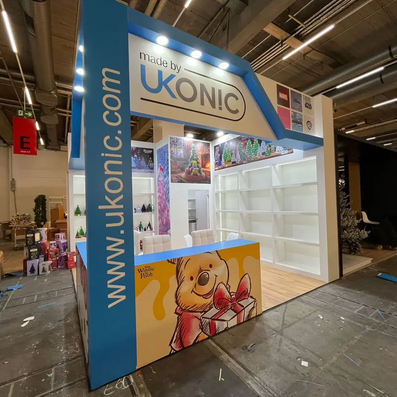 Blau-weißer Messestand mit großflächigen Produktgrafiken und weißen Wandregalen.