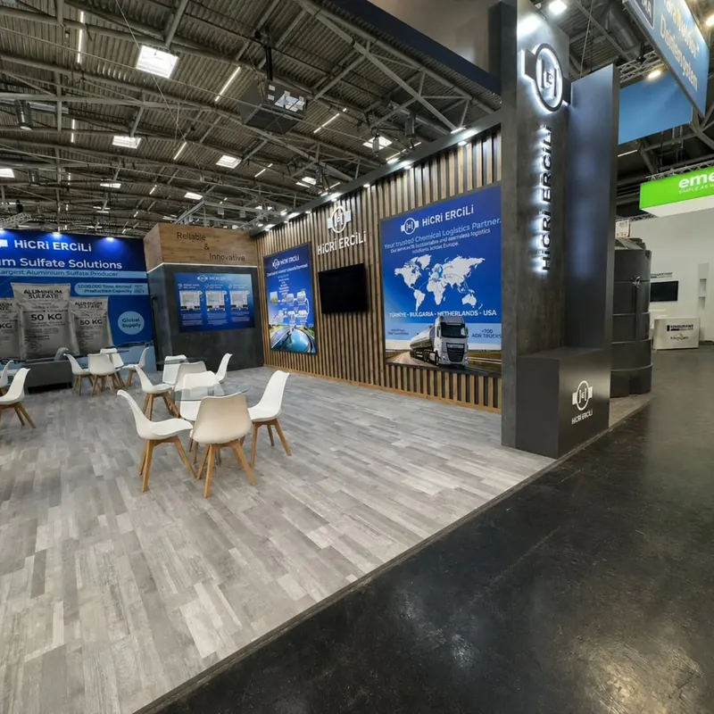 Messestand mit Holzlamellen, blauen Informationstafeln und weißen Sitzgruppen auf grauem Boden.