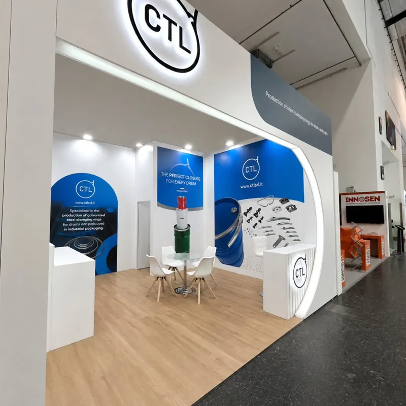 Weiß-blauer Messestand mit hohem Portal, Holzoptikboden und Produktpodesten.