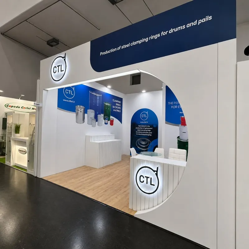 Weißer Messestand mit rundem Durchgang, blauen Wandgrafiken und geschwungener Empfangstheke.