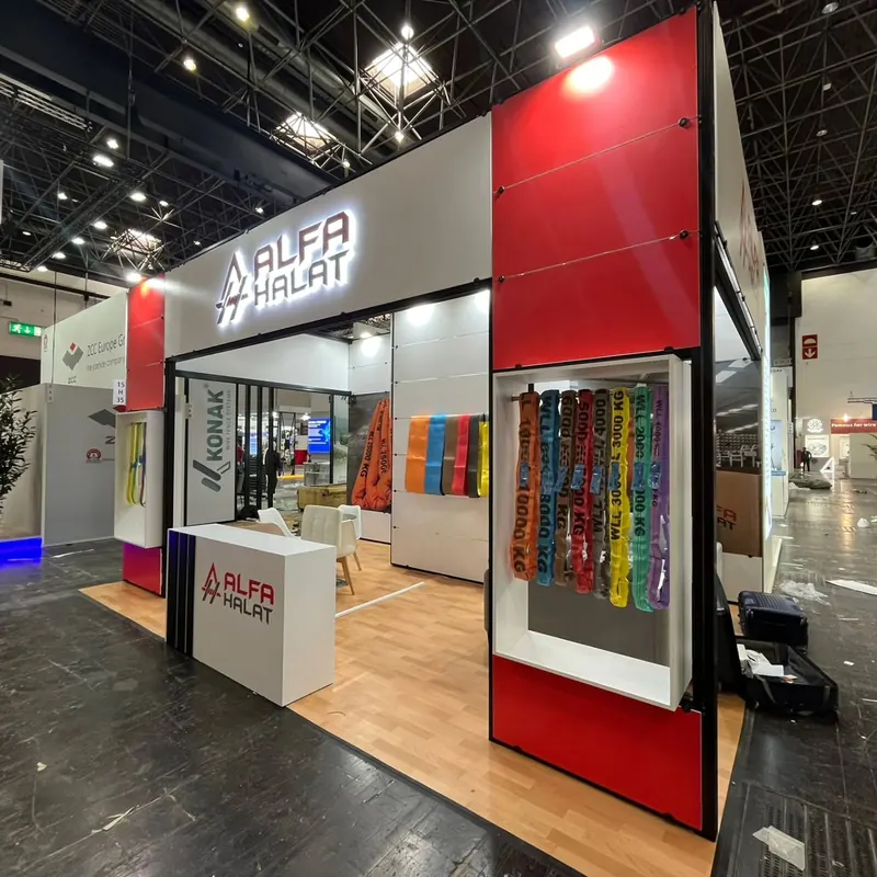 Rot-weißer Messestand mit hoher Ecke, Glasvitrinen und farbigen Produktmustern.