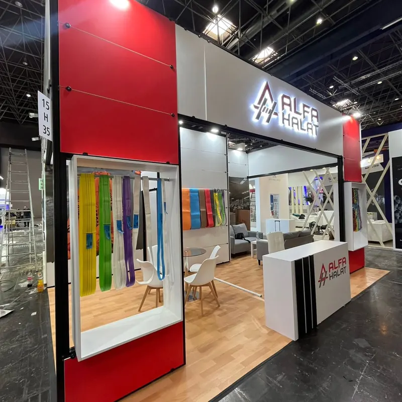 Rot-weißer Messestand mit Glasvitrine für bunte Muster und weißer Empfangstheke.
